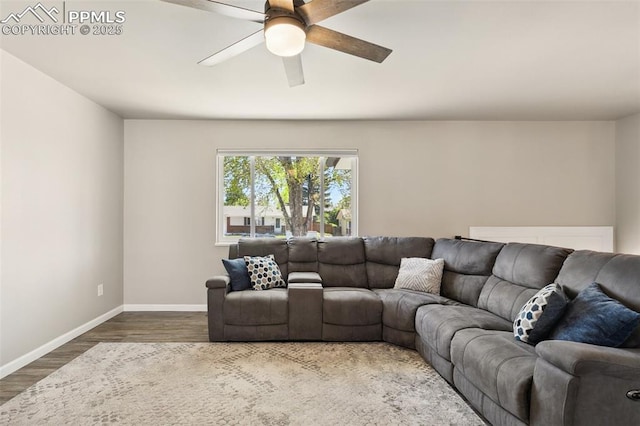 living area featuring a ceiling fan, baseboards, and dark wood finished floors