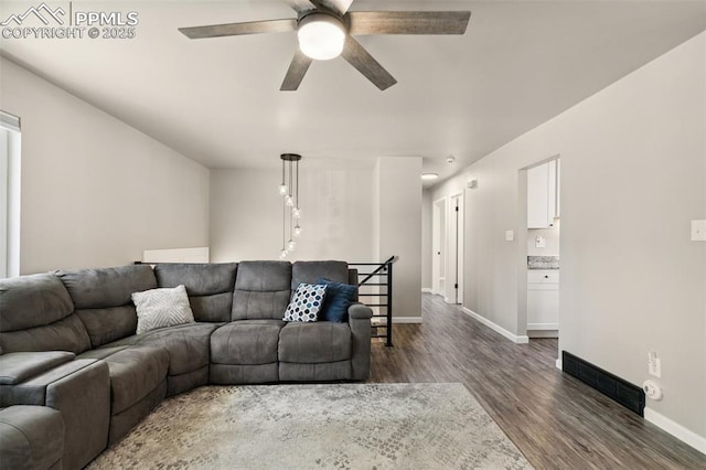 living area featuring baseboards, visible vents, dark wood-style flooring, and a ceiling fan