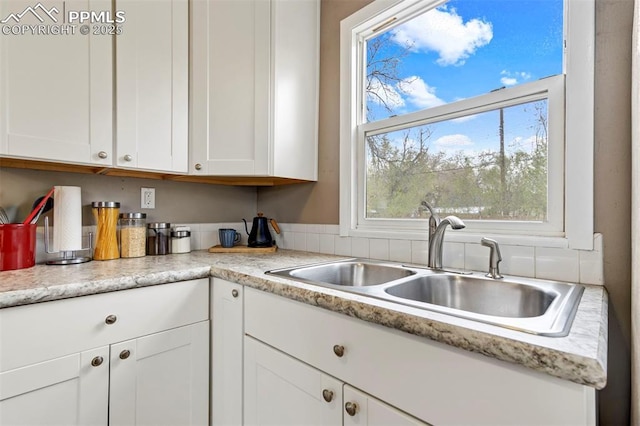 kitchen with white cabinetry, plenty of natural light, light countertops, and a sink