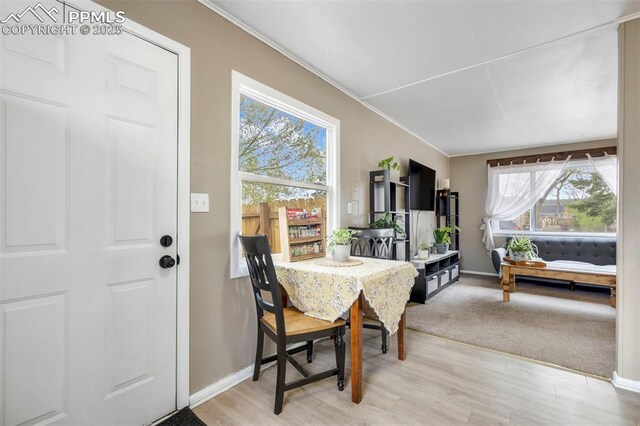 dining room with baseboards, light wood-type flooring, and ornamental molding
