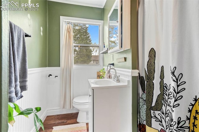 bathroom with crown molding, a wainscoted wall, toilet, wood finished floors, and vanity