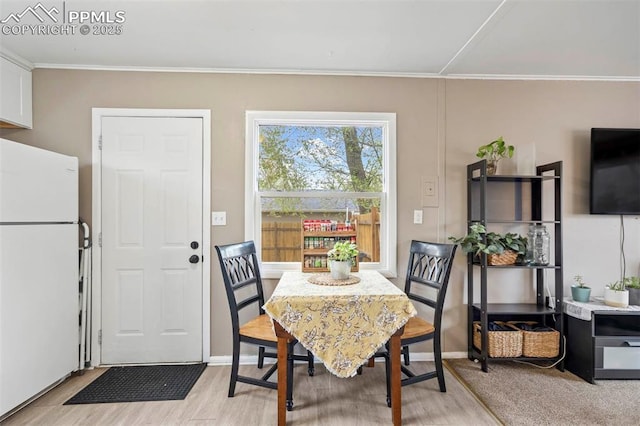 dining area featuring light wood-type flooring, crown molding, and baseboards