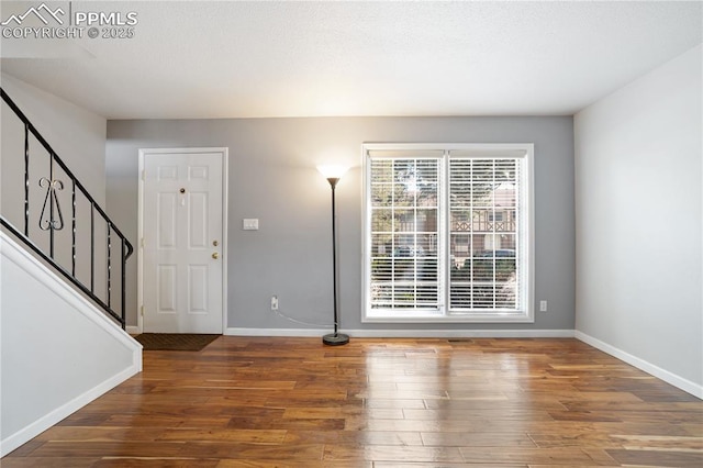 foyer entrance featuring baseboards, stairway, and wood finished floors
