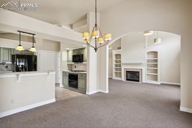 kitchen with black appliances, a breakfast bar area, light carpet, an inviting chandelier, and green cabinetry