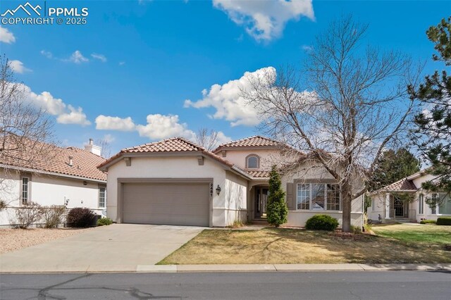 mediterranean / spanish-style house featuring a tile roof, concrete driveway, a front lawn, a garage, and stucco siding