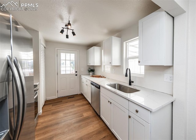 2204 Bonfoy Ave, Colorado Springs, CO 80909 - kitchen featuring light wood finished floors, stainless steel appliances, a sink, and white cabinetry