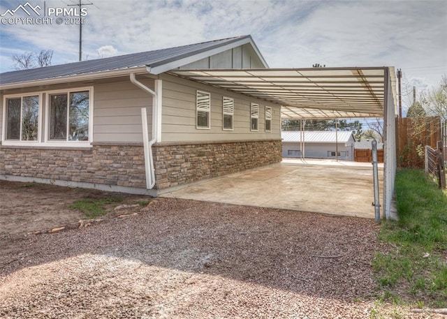 2204 Bonfoy Ave, Colorado Springs, CO 80909 - view of side of home with fence, driveway, an attached carport, stone siding, and metal roof