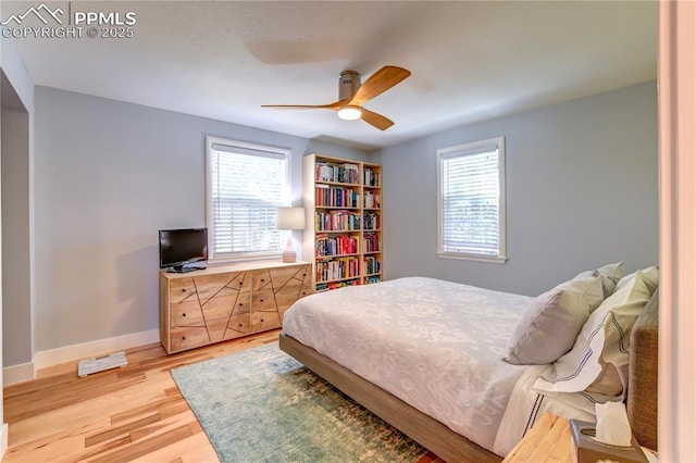 bedroom featuring light wood-style floors, a ceiling fan, baseboards, and multiple windows