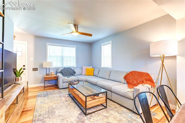 living area featuring ceiling fan, baseboards, and light wood-type flooring