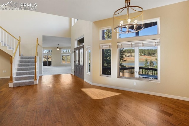 foyer entrance with baseboards, stairs, a towering ceiling, and wood finished floors
