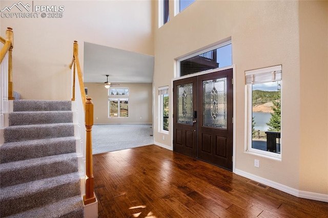entryway with ceiling fan, hardwood / wood-style flooring, baseboards, a high ceiling, and stairs