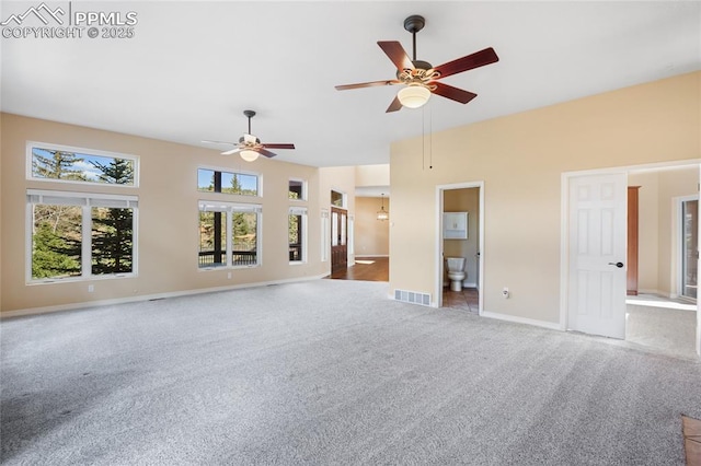 unfurnished living room featuring visible vents, a towering ceiling, baseboards, a ceiling fan, and carpet