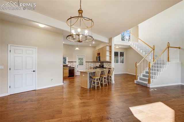 kitchen with tasteful backsplash, open shelves, wood finished floors, dishwasher, and a notable chandelier