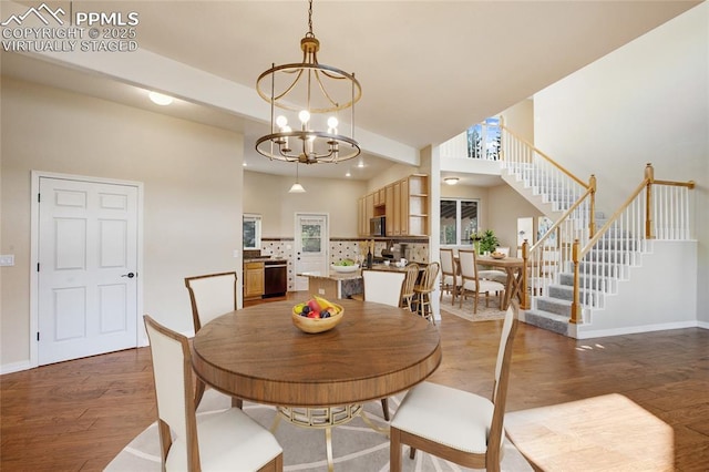 dining space featuring stairway, baseboards, an inviting chandelier, and wood finished floors