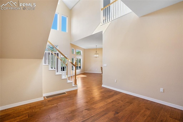 entrance foyer featuring a towering ceiling, visible vents, wood finished floors, stairway, and baseboards