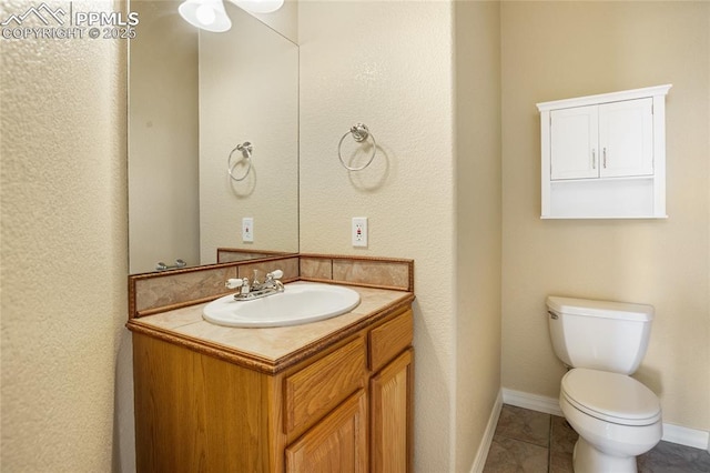 half bath with vanity, baseboards, tile patterned floors, and toilet