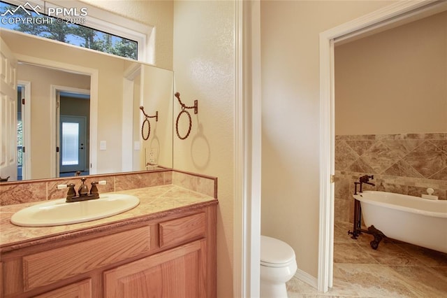 bathroom with a freestanding bath, vanity, tile patterned floors, and toilet