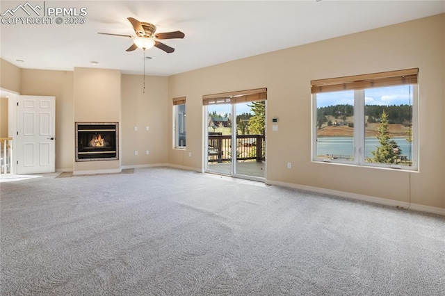 unfurnished living room with carpet floors, a ceiling fan, and a wealth of natural light