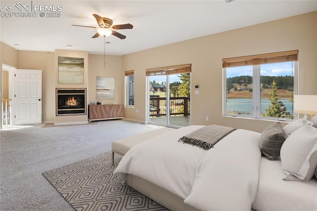 carpeted bedroom featuring baseboards, a glass covered fireplace, multiple windows, and access to exterior