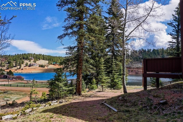 view of yard with a water view, fence, and a forest view