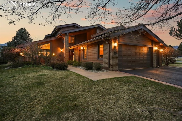 view of front of house with brick siding, aphalt driveway, a front yard, and an attached garage
