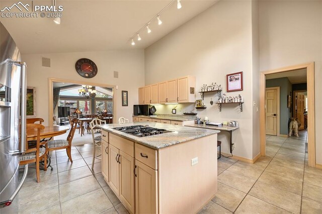 kitchen featuring high vaulted ceiling, light tile patterned floors, gas cooktop, and a kitchen island