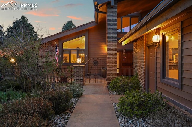 exterior entry at dusk featuring brick siding