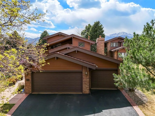 chalet / cabin with aphalt driveway, a mountain view, and brick siding