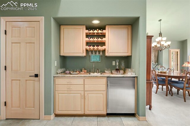 bar with a chandelier, stainless steel fridge, indoor wet bar, a sink, and baseboards
