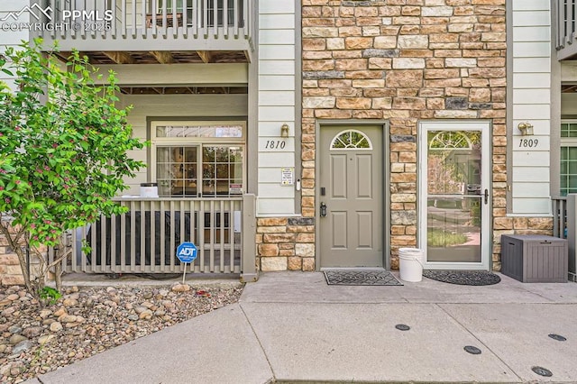 doorway to property featuring covered porch and stone siding