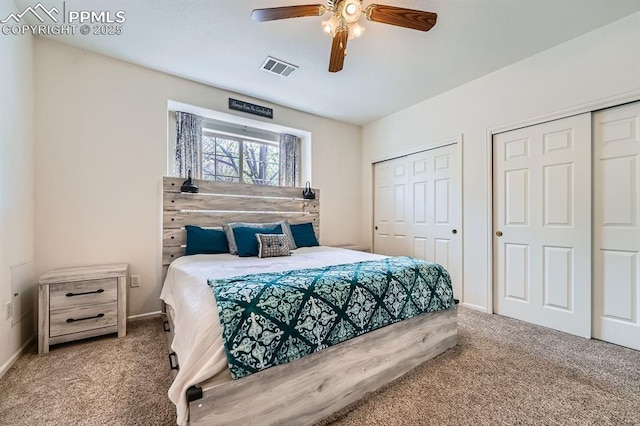 carpeted bedroom with visible vents, a ceiling fan, baseboards, and two closets