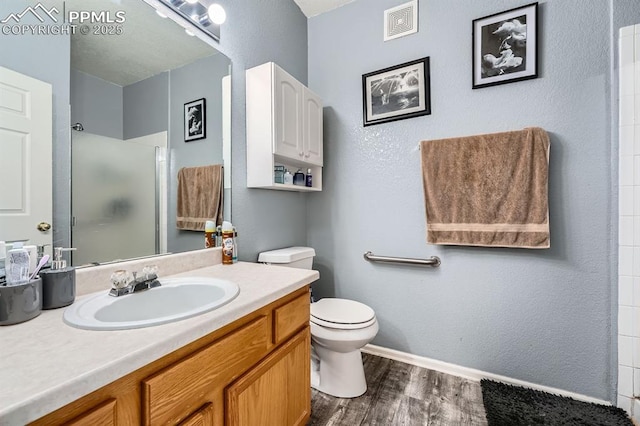 bathroom featuring visible vents, vanity, wood finished floors, toilet, and a stall shower