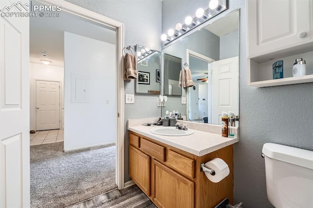bathroom with vanity, a textured wall, and toilet