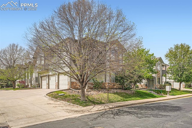 view of property hidden behind natural elements featuring concrete driveway and a garage