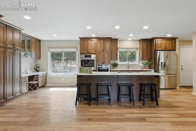 kitchen featuring a breakfast bar area, stainless steel appliances, light wood-style flooring, and light countertops