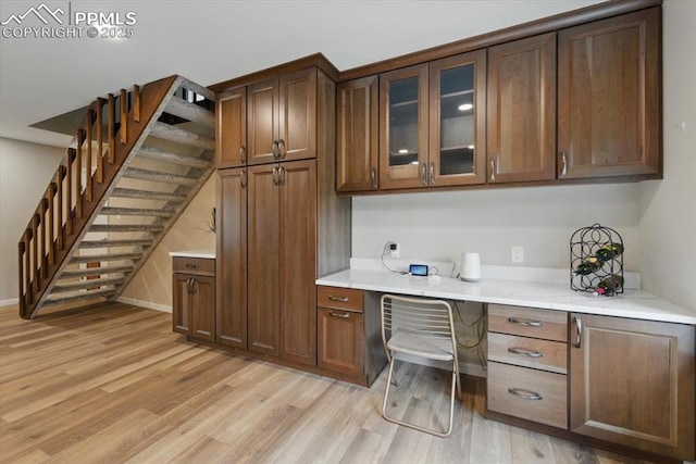 interior space with baseboards, light wood-type flooring, and built in desk