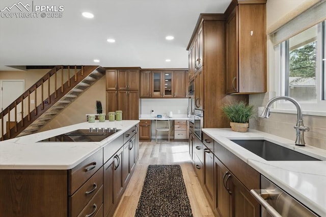 kitchen featuring appliances with stainless steel finishes, a sink, a center island, recessed lighting, and light wood-type flooring