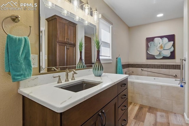 full bathroom with a garden tub, wood finished floors, and vanity