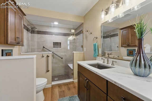 bathroom featuring vanity, wood finished floors, toilet, and a shower stall