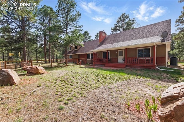 rear view of property featuring a porch, fence, and a chimney