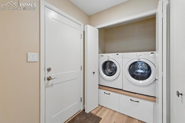 washroom with laundry area, washing machine and dryer, and light wood-type flooring