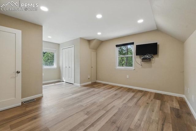 additional living space with baseboards, plenty of natural light, wood finished floors, and visible vents