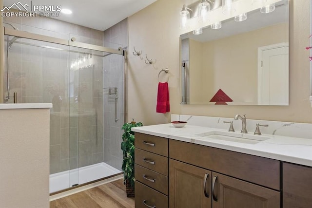 full bathroom featuring a shower stall, wood finished floors, and vanity