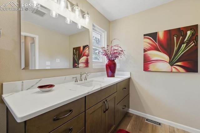 bathroom with baseboards, visible vents, wood finished floors, and vanity
