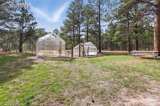 view of yard featuring an outbuilding, fence, and a greenhouse