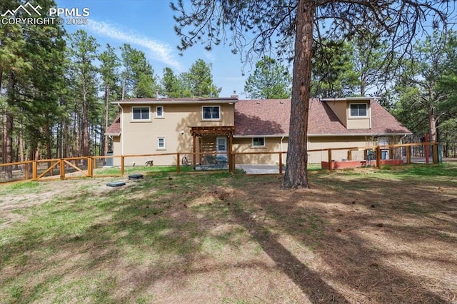 back of property with a fenced backyard, a gate, stucco siding, and a yard