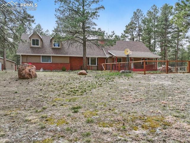 back of property featuring brick siding and a shingled roof