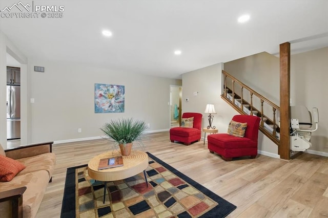 living room featuring baseboards, recessed lighting, light wood finished floors, and stairs