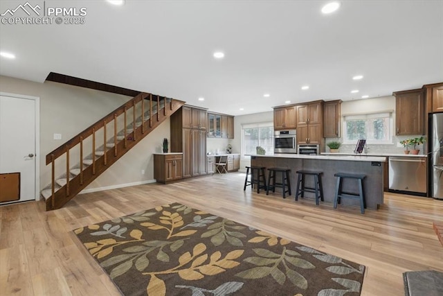 kitchen featuring light countertops, light wood finished floors, a kitchen breakfast bar, and stainless steel appliances