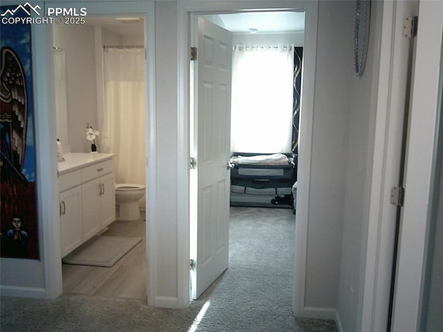 hall featuring light colored carpet and baseboards